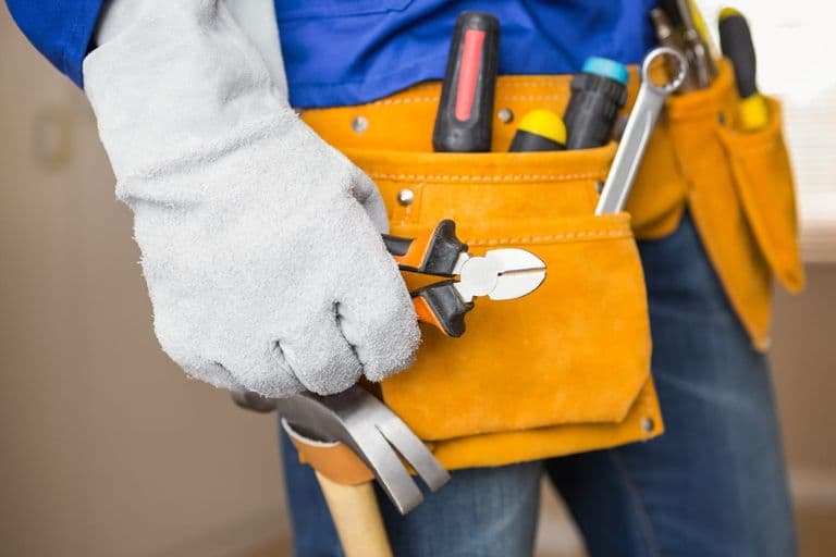 A handyman’s tool belt with pliers, screwdrivers and a hammer