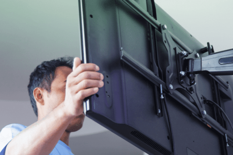 A man fitting a TV to a wall bracket