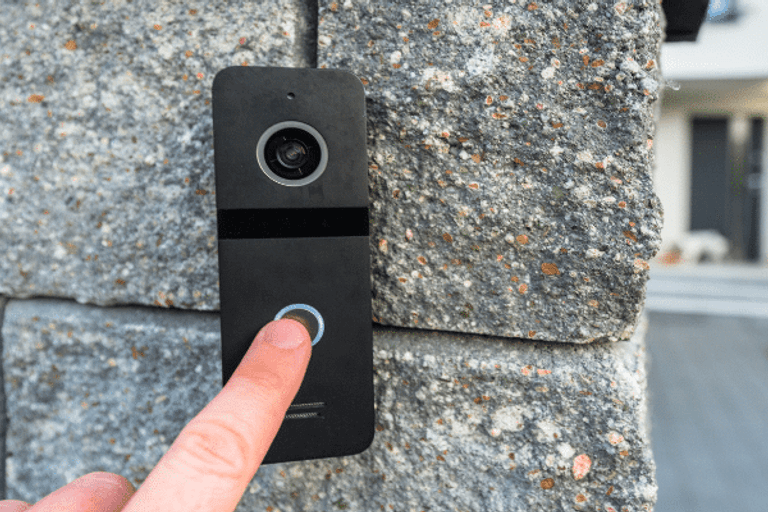 A finger pressing a video doorbell