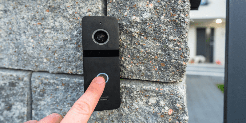 A finger pressing a video doorbell