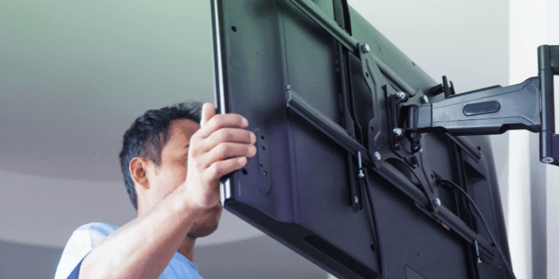 A man fitting a TV to a wall bracket